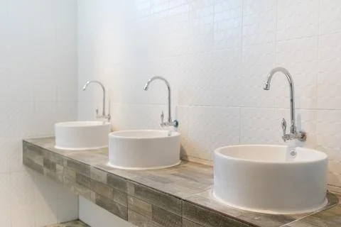 Three sinks on wood pattern tiles counter in bathroom.. Stock Photos