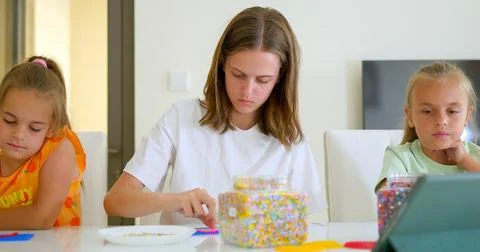 Three sister, of variable age putting the mosaic together on the table 库存照片