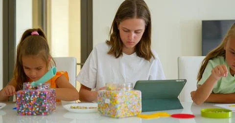 Three sister, of variable age putting the mosaic together on the table 库存照片