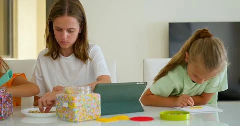 Three sister, of variable age putting the mosaic together on the table 库存照片