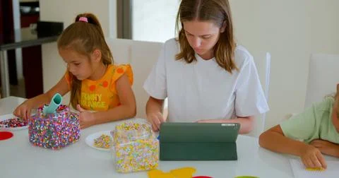 Three sister, of variable age putting the mosaic together on the table 库存照片