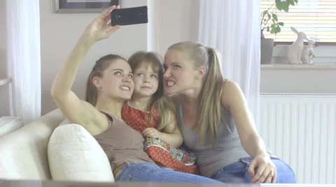 Three sisters in different age at home holding up a smartphone to take a picture Stock Footage 40519325