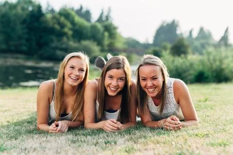 Three sisters laying down in grass smiling and laughing Stock Photos