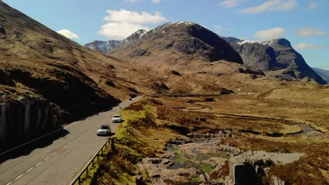 Three Sisters mountain range towering above Glencoe river and road on sunny day 库存影片 341476330