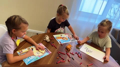 Three sisters triplets drawing with felt-tip pens on A4 sheets sitting at home Video stock 266308009