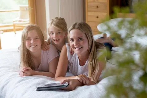 Three sisters using a digital tablet at home Stock Photos