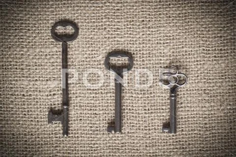 Three Skeleton Keys On Burlap Background