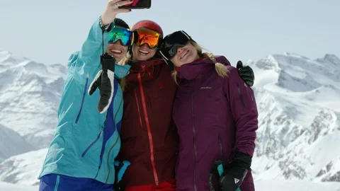Three skiers posing for selfie after skiing on sunny day surrounded by mountains Stock Footage 116787853
