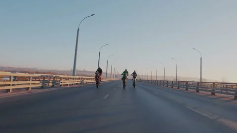 Three skilled motorcyclists simultaneously ride on the rear wheel at the same Stock Footage 105011289