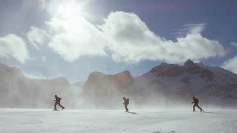 Three skilled skiers walking on the snow covered mountains on a sunny day Stock Footage 116787035