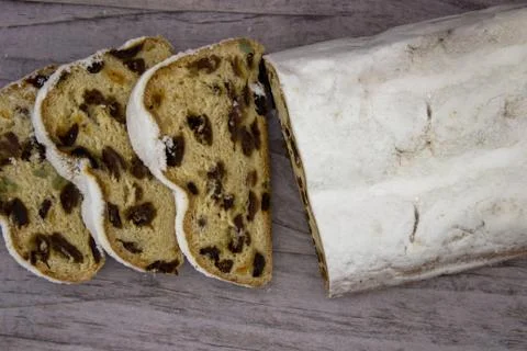 The three slices and the main part of Stollen on a wooden background. Traditi Stock Photos