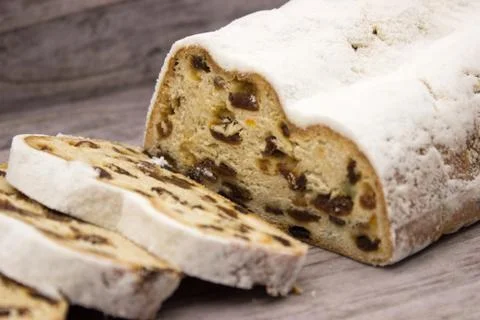 The three slices and the main part of Stollen on a wooden background. Traditi Stock Photos