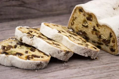 The three slices and the main part of Stollen on a wooden background. Traditi Stock Photos