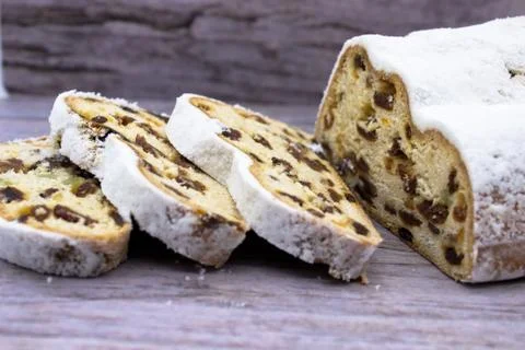 The three slices and the main part of Stollen on a wooden background. Traditi Stock Photos