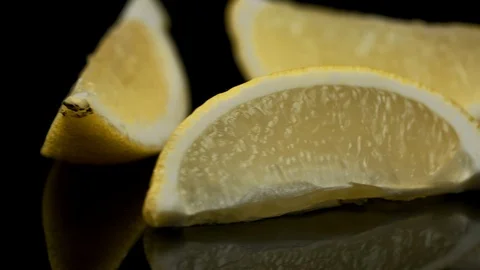 Three slices of lemon rotating on a black background Stock Footage 128721667