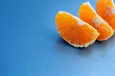 Three slices of mandarin on a blue background Foto stock