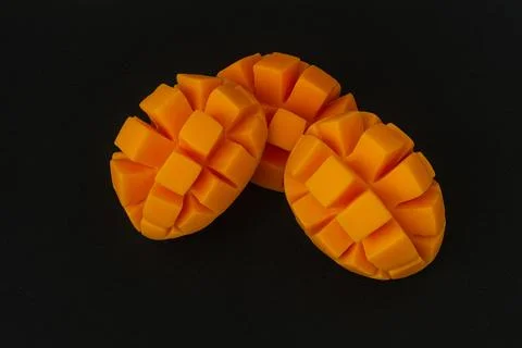 Three slices of orange mango with cut parts, isolated on a dark black backgro Stock Photos