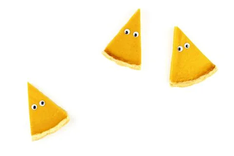 Three slices of pumpkin pie in form of Halloween ghost with eyes on white Stock Photos