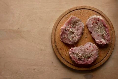 Three slices of raw meat on round cutting board Stock Photos