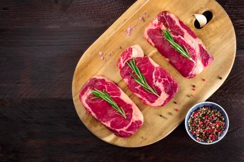 Three slices of raw meat on rustic textures with seasoning 写真素材