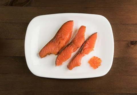 Three slices of red fish and caviar on a white plate Stock Photos