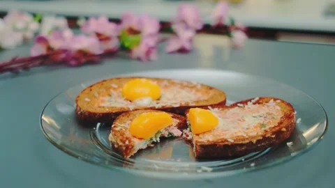 Three slices of toasted bread topped with runny egg yolks on glass plate Видео 342866207