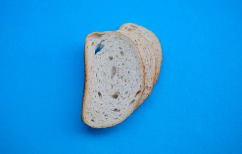 Three slices of white wheat bread on a blue background. Stock Photos