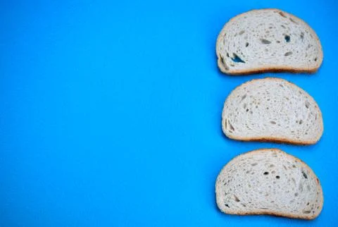 Three slices of white wheat bread on a blue background. Stock Photos