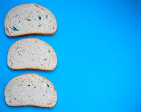 Three slices of white wheat bread on a blue background Stock Photos