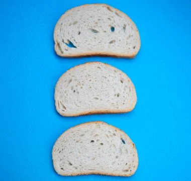 Three slices of white wheat bread on blue background Stock Photos