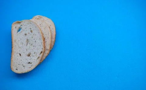 Three slices of white wheat bread on blue background. Stock Photos