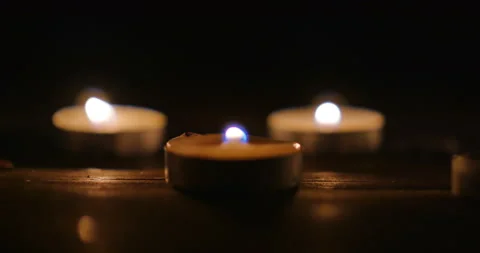 Three small burning tealight candles in the darkness Video stock 152415336