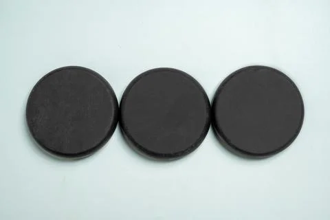 Three small, circular, black industrial ferrite magnets arranged in a horiz.. Stock Photos