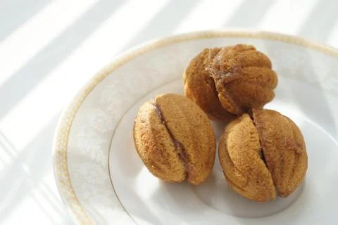 Three small cookies in the form of walnuts on a white saucer and a sunny tabl 스톡 사진