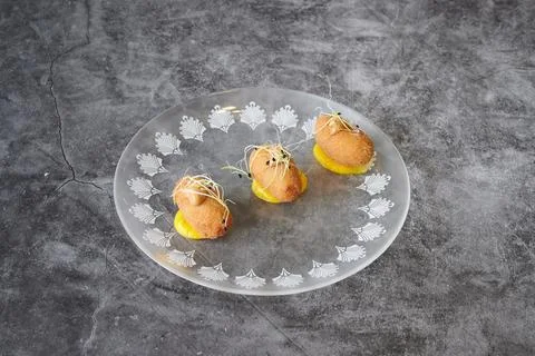 Three small fried dough balls are on a white plate with a pattern 스톡 사진