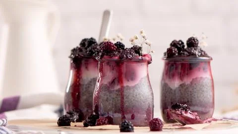 Three Small Glass Jars of Chia Pudding with Blackberry Compote and Fresh Be.. Stock Photos