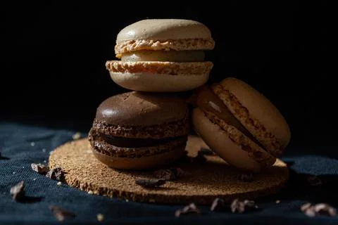 Three small multi-colored macaroons on a dark background, a sweet treat Stock Photos
