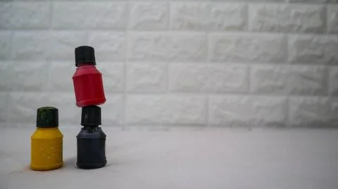 Three small paint bottles in black, yellow, and red colors are arranged in .. Stock Photos