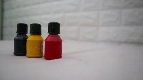 Three small paint bottles in black, yellow, and red colors are arranged in .. Foto stock
