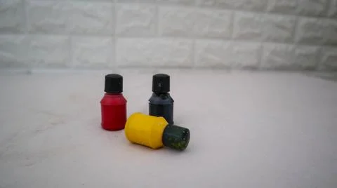 Three small paint bottles in black, yellow, and red colors are arranged in .. Foto stock