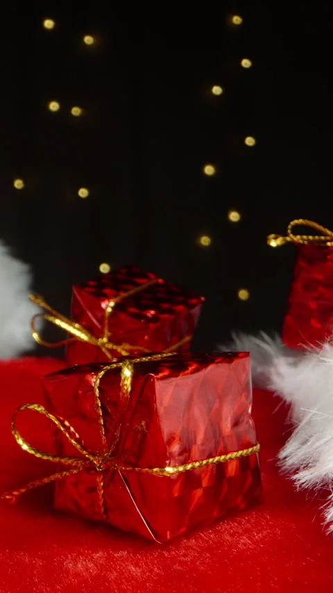 Three small red gift boxes rest on Santa's hat against the backdrop of a flicker Vídeos de archivo 249029808