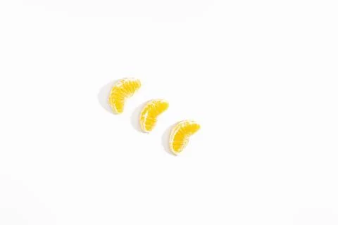 Three small slices of tangerine lie diagonally on a white background. View from Stock Photos