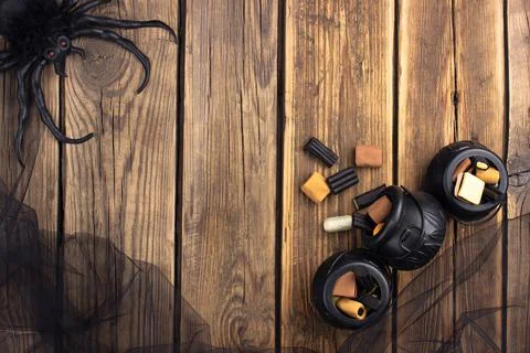 Three small toy witch's cauldrons with different sweets are on a wooden table Stock Photos