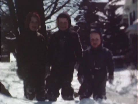 Three smiling children in snowsuits standing in the snow - Vintage 8mm Stock Footage 78933831