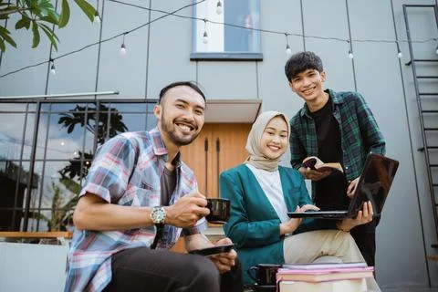 Three smiling college students using a laptop in a cafe Stock-Fotos