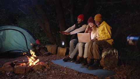 Three smiling people using laptop during campsite sitting together on winter Stock Footage 256041332