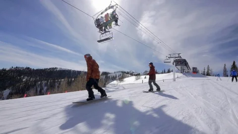 Three snowboarders ride down, sunny winter slope, Park City, UT. Stock Footage 99998461