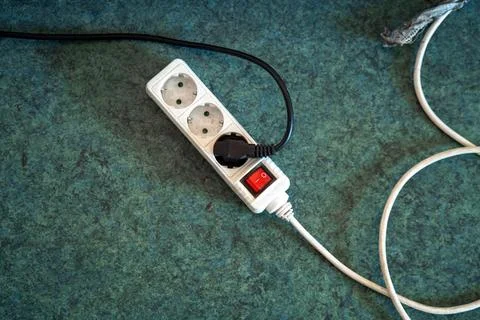 Three-socket power strip on a dirty floor, highlighting the contrast betwee.. Stock Photos