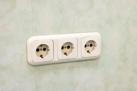 Three sockets on a green wall closeup Stock Photos