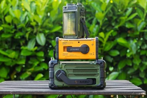 Three Solar-Powered Portable Radios Displayed on a Wooden Surface Outdoors Stock Photos